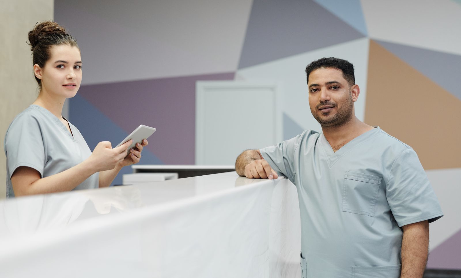 Staff at a clinic front desk handling records on a tablet